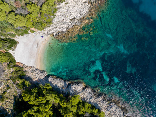 istock TOP DOWN: Flying high above a pebble beach and the turquoise Mediterranean sea. 2152087526