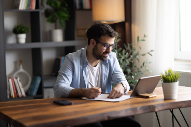 istock A serious male remote online manager discussing current issues with his coworkers through a video call on his tablet. 2152091701