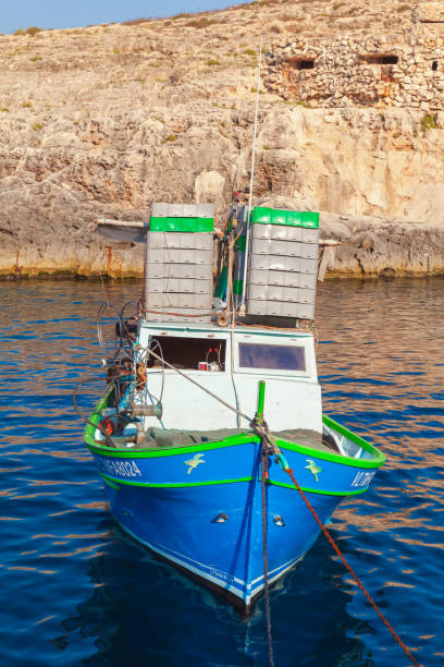 Blue Grotto, Malta - August 22, 2019: Small fishing boat with boxes for catch is anchored on a sunny summer day, Blue Grotto bay