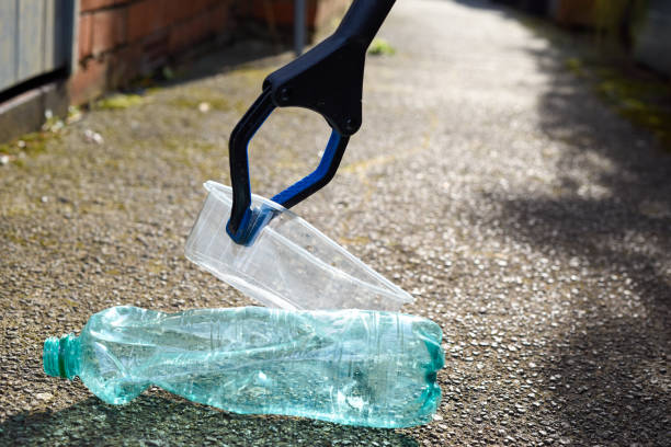 Picking up plastic waste and rubbish which has been dropped on the pavement to clean up and care for the environment