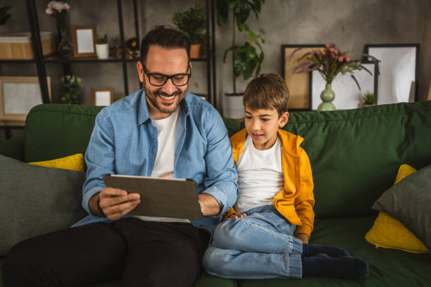 istock Father with eyeglasses and son use tablet for homework browse internet 2152098364
