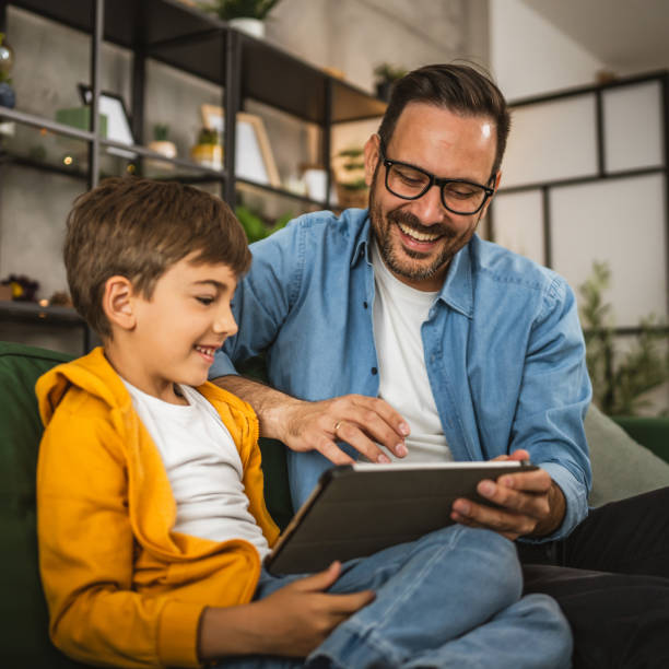Father with eyeglasses and son use tablet for homework browse internet