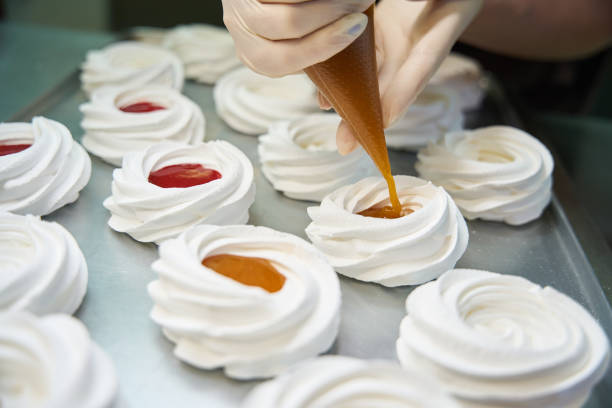 istock Confectioner filling airy and crispy merengues with fresh fruit mousse 2152103087
