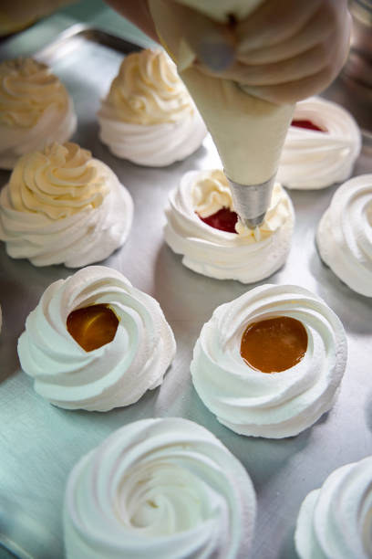 istock Confectioner squeezing whipped cream on top of merengue nest 2152103093