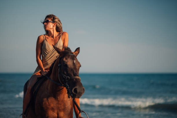 istock Woman model on horseback on the sandy coastline during a summer 2152105840