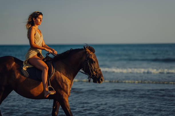 istock Side view of a woman galloping on a horse on a beach 2152105842