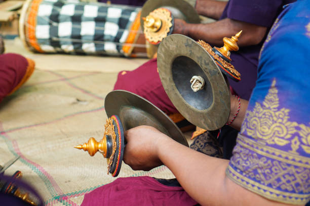 Close-up view of a musician's hands using cymbals called ceng-ceng at a Balinese ceremony, emphasizing the detailed craftsmanship of these traditional instruments