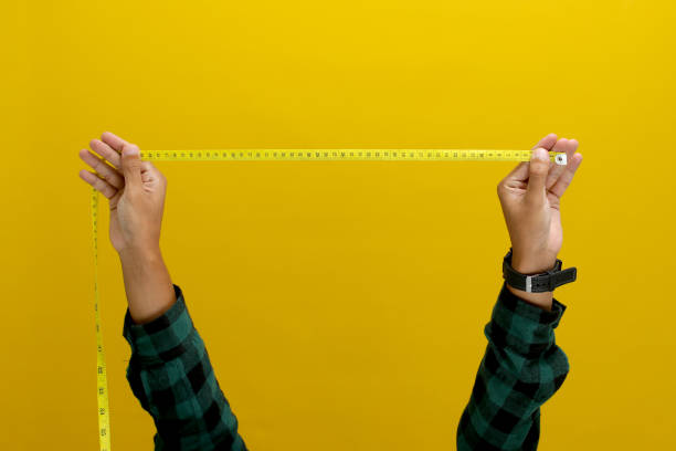 istock Hand holding a measuring tape against a yellow background 2152115206
