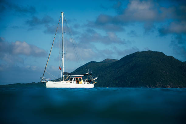 Contrasting white boat floating in dark blue ocean water near an island