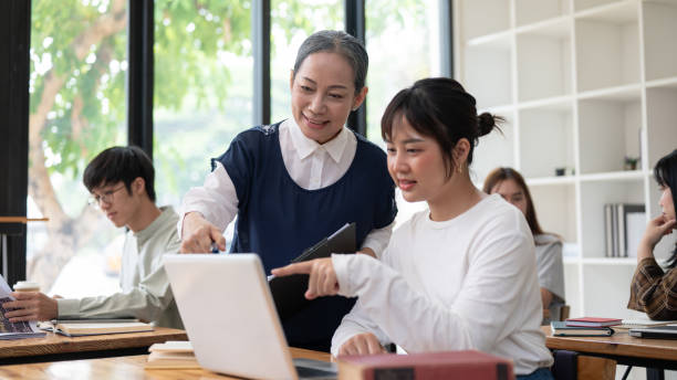 istock A mature Asian female teacher or professor helping and explaining a difficult question to a student. 2152120727