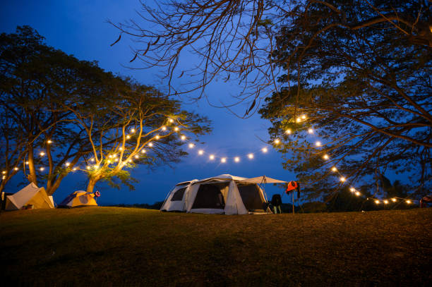 istock camping tent on grass courtyard and warm night light under dark blue sky. Family vacation picnic on holiday relax. 2152122385