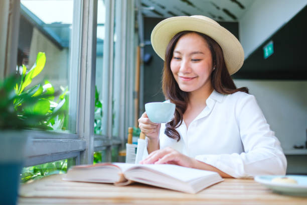 istock Portrait image of a beautiful young woman with hat drinking coffee while reading book 2152122765