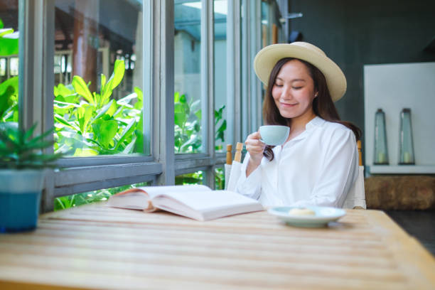 istock Portrait image of a beautiful young woman with hat drinking coffee while reading book 2152122770