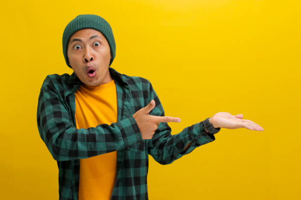 istock An excited young Asian man points at his open palm showcasing empty copy space for product 2152130170
