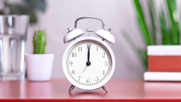 istock Classic white clock on a table. The clock hand points at 12:00, 00:00 close up photo interior 2152131743