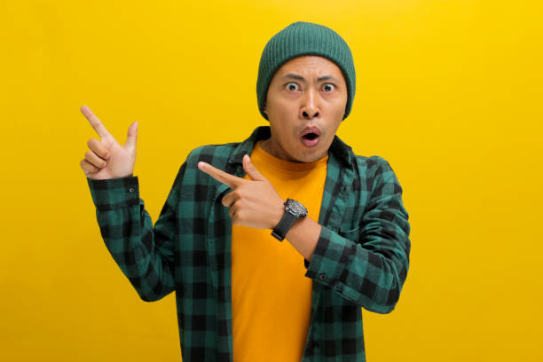 istock An excited young Asian man points his finger to the left at an empty copy space 2152132215