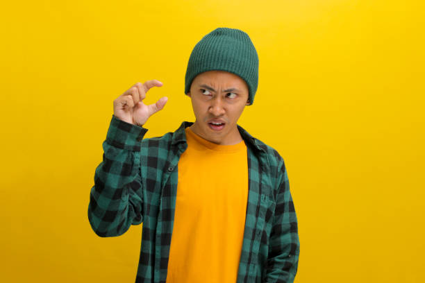 istock Displeased Asian man is gesturing a small size with his finger, indicating something not very big 2152133668
