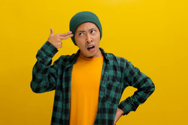 istock Distressed young Asian man is showing finger pistol gestures above his head 2152133918