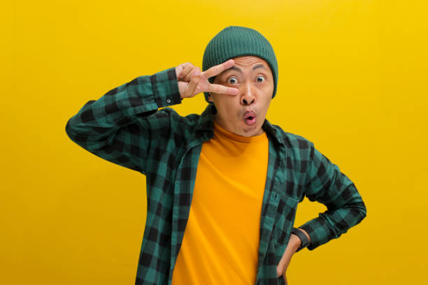 istock Excited young Asian man is making a peace gesture towards camera with a V sign 2152135290
