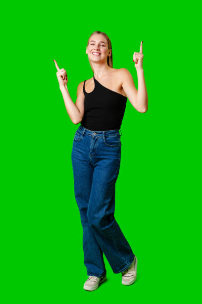 istock Young Woman Pointing Up Against Green Background 2152135514