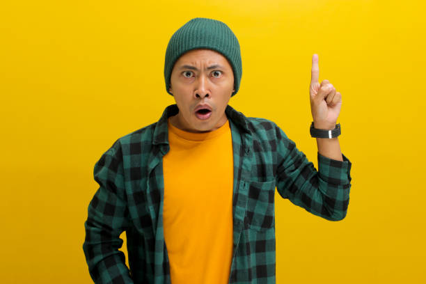 istock Surprised young Asian man is pointing his finger up at an empty copy space 2152135851