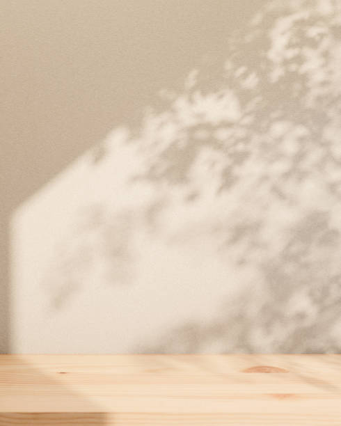 istock A minimal wooden board or tabletop is set against the white wall, with leaf shadows and sunlight. 2152136674