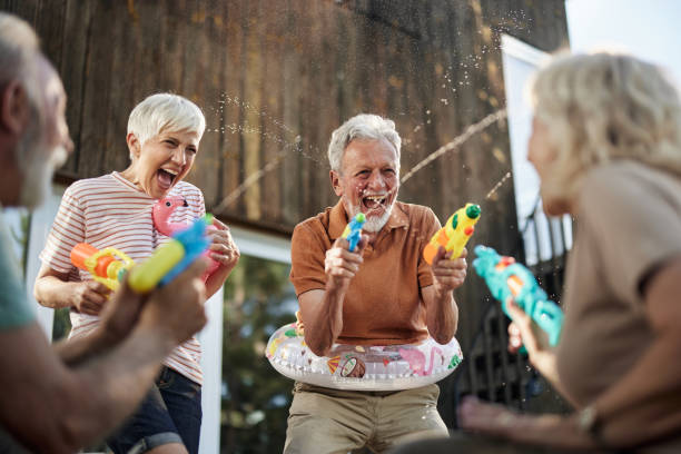 Happy senior couples having fun during water gun fight on a terrace.