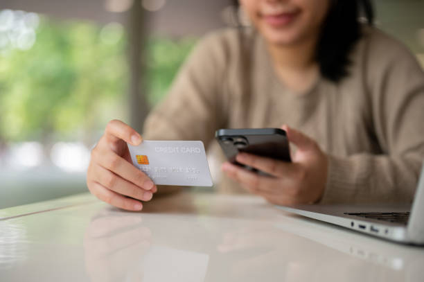 istock A young happy Asian woman using her mobile banking app while sitting at a table indoors. 2152139026