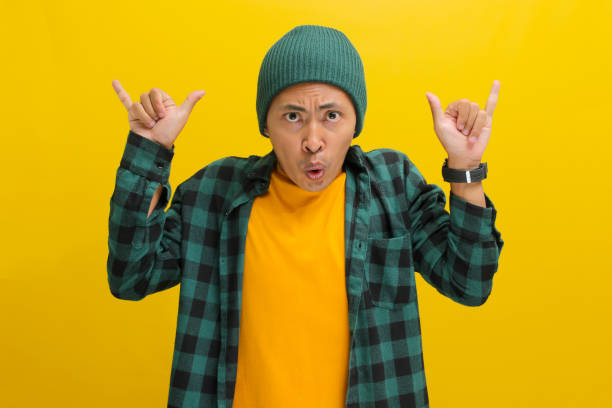 istock Young Asian man is making a rock gesture with his hand and a smile at the camera 2152139428