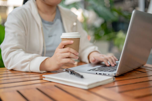istock An Asian woman working remotely at a cafe, sipping coffee while working on her computer. 2152142748