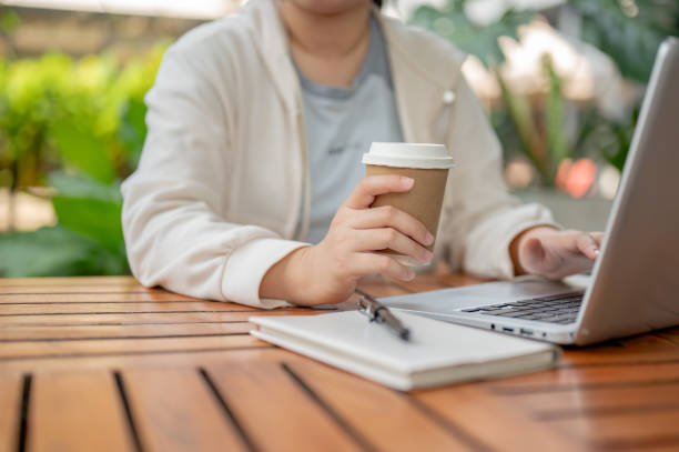 istock An Asian woman working remotely at a cafe, sipping coffee while working on her computer. 2152142750