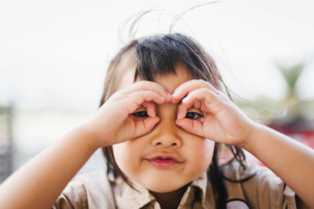Smiling Asian teenager kid use binoculars search for opportunities isolated on white background with clipping path.