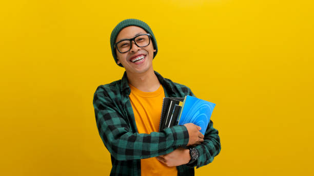 istock A young Asian student holding books against his chest. 2152143441