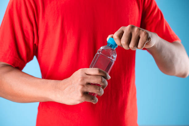 istock Close-up of man hand holding water bottle isolate on blue background. 2152144012