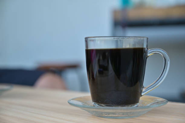 Glass cup of black coffee close up view with blur background