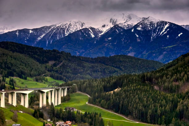 Scenic view of brenner highway stretching across verdant valleys with snow-capped mountains in the backdrop