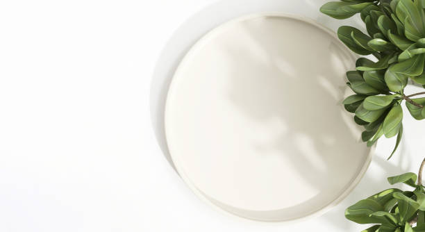 istock Top view of cream plate tray on white table counter, green tropical tree in sunlight, leaf shadow 2152150080