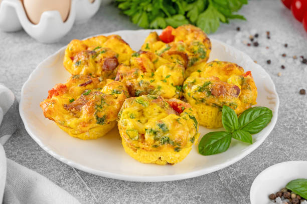 istock Egg muffins or egg bites with bacon, cheese, vegetables and herbs on a white plate on a concrete background. Healthy breakfast. 2152150118