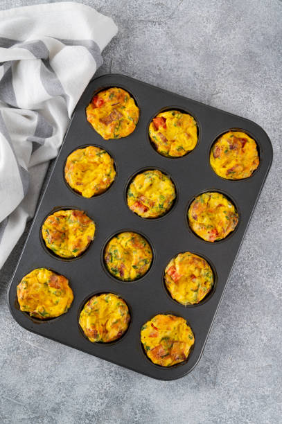 istock Egg muffins or egg bites with bacon, cheese, vegetables and herbs in a baking form on a concrete background. Healthy breakfast. 2152150124