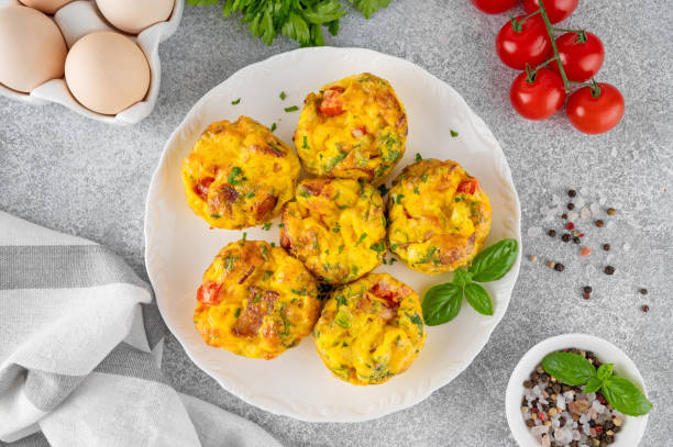 istock Egg muffins or egg bites with bacon, cheese, vegetables and herbs on a white plate on a concrete background. Healthy breakfast. 2152150151