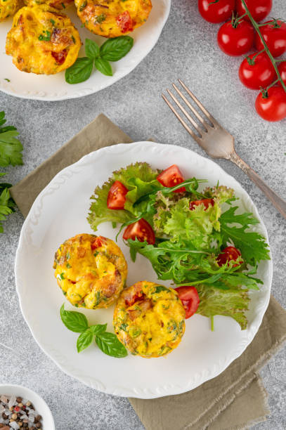 istock Egg muffins or egg bites with bacon, cheese, vegetables and herbs on a white plate on a concrete background. Healthy breakfast. 2152150158
