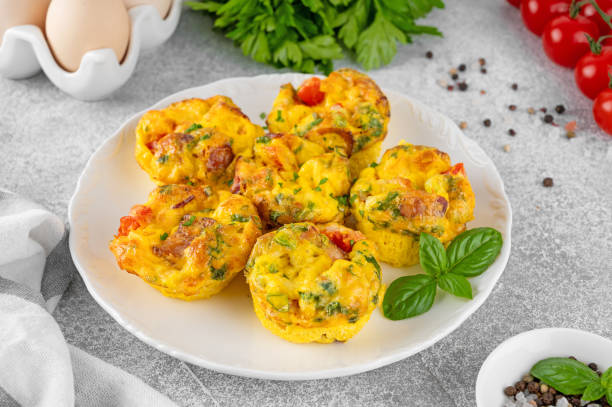 istock Egg muffins or egg bites with bacon, cheese, vegetables and herbs on a white plate on a concrete background. Healthy breakfast. 2152150164