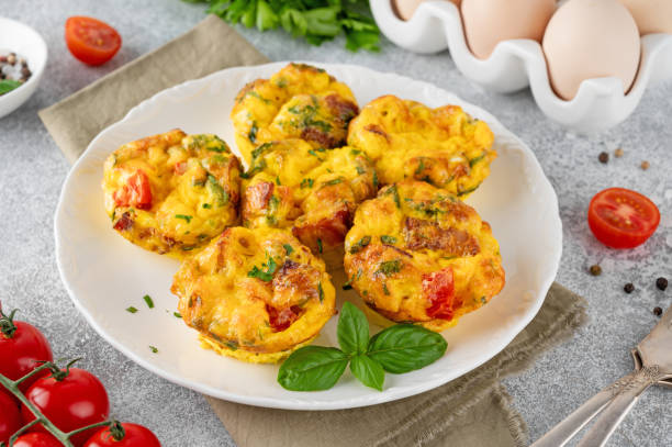 istock Egg muffins or egg bites with bacon, cheese, vegetables and herbs on a white plate on a concrete background. Healthy breakfast. 2152150175