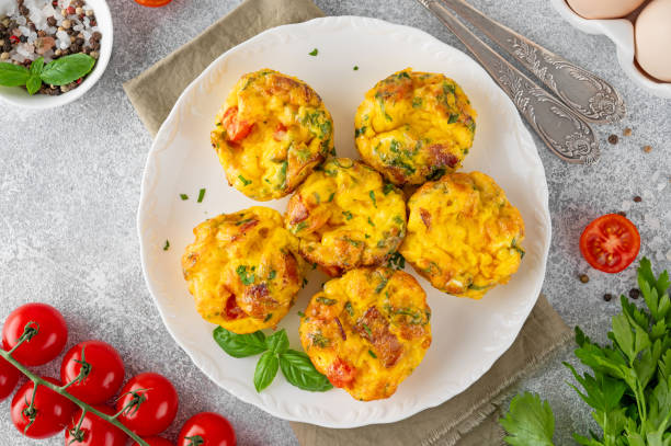 istock Egg muffins or egg bites with bacon, cheese, vegetables and herbs on a white plate on a concrete background. Healthy breakfast. 2152150176