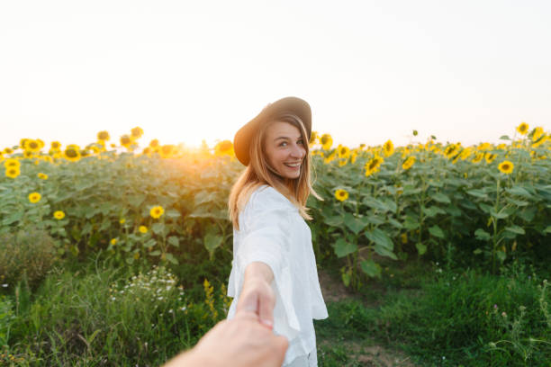Photo of a mid adult woman, enjoys walking down the sunflower field