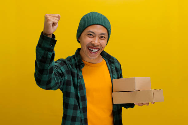 istock Happy Asian customer raises his arm in a YES gesture while holding package parcel cardboard box 2152151328