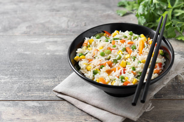istock White rice with vegetables in a black bowl on wooden table 2152151531