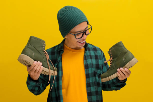 istock Happy Asian man joyfully unboxes a parcel package containing new shoes against a yellow background 2152151543