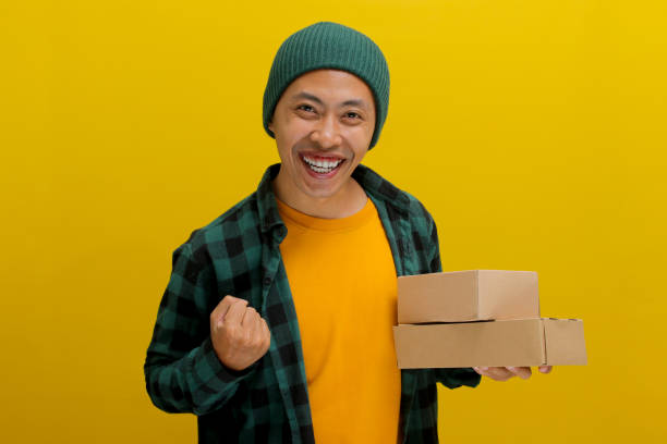 istock Happy Asian customer raises his arm in a YES gesture while holding package parcel cardboard box 2152151648