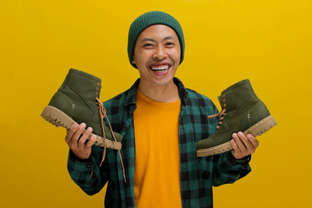 istock Happy Asian man joyfully unboxes a parcel package containing new shoes against a yellow background 2152151898